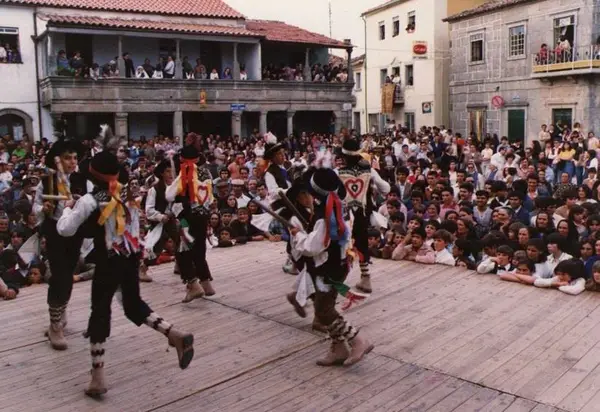 Pauliteiros num palco de madeira na praça, com a bila à volta e nas varandas