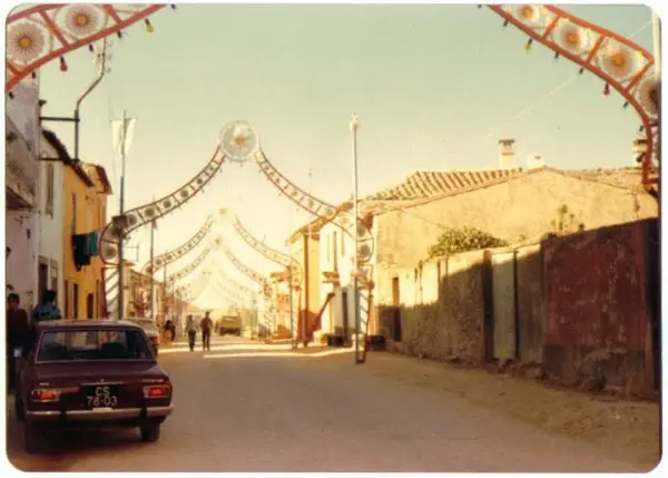 Rua em dia de festa, com arcos e bandeirinhas de ponta a ponta