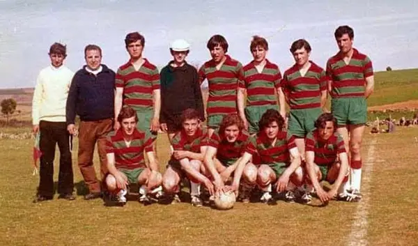 Equipa de futebol posada no campo, de camisola às riscas encarnadas e verdes