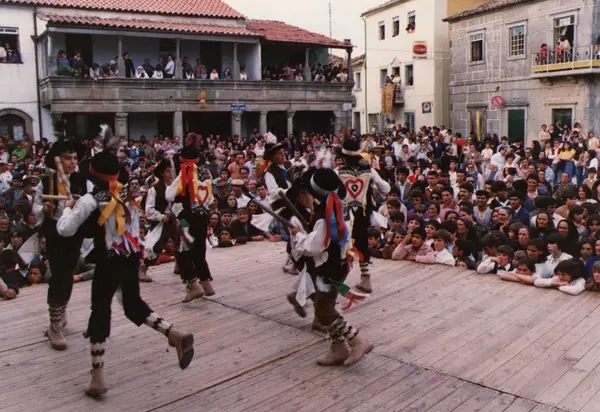 Pauliteiros num palco de madeira, vistos de cima, com a praça cheia