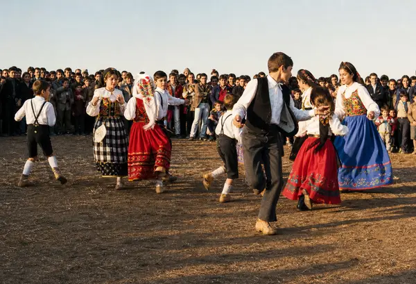 Par de dançarinos de traje a rodopiar, com a gente à volta