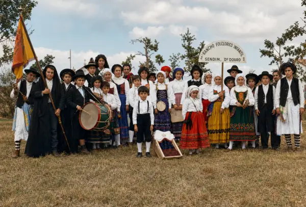 Rancho folclórico posado debaixo do arco, com a bandeira