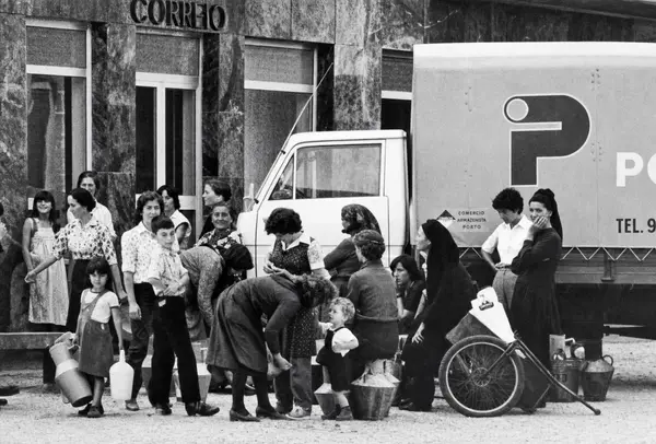 O carro dos correios parado à porta, com mulheres e crianças à volta