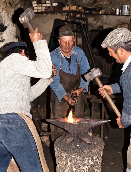 Na frauga: um segura o ferro em brasa, os outros dois malham à vez
